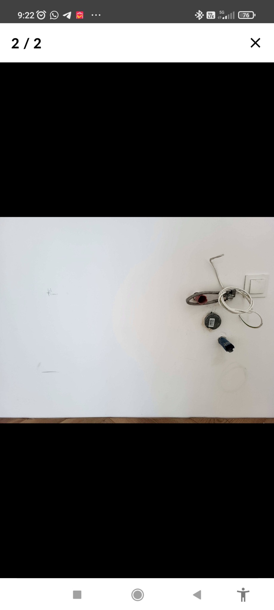 Biała ściana z widocznymi elementami instalacji hydraulicznej: rurka, przewody, puszka. Widoczne ślady po pracach instalacyjnych. Ujęcie z bliska, bez detali wykończeniowych.