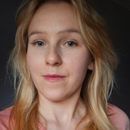 Osoba prywatna - Portret kobiety o jasnych włosach i niebieskich oczach, ubrana w różową koszulkę, na ciemnym tle. Naturalny makijaż, delikatny uśmiech.