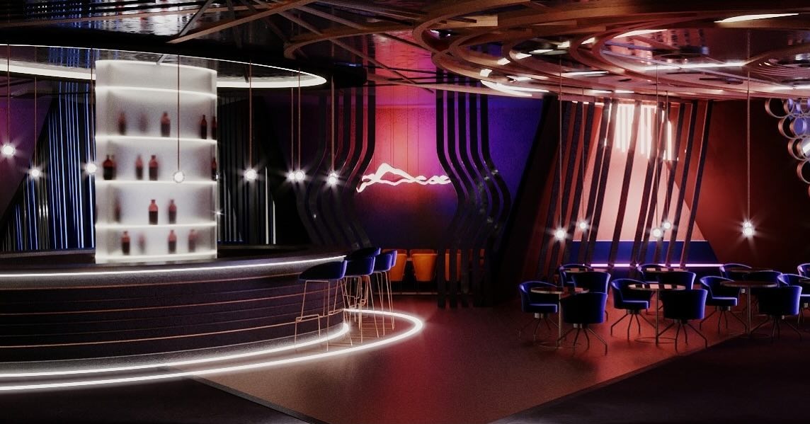 Nowoczesny bar muzyczny z podświetlanym barem, półkami na butelki i ciemnymi krzesłami. Neonowe logo na ścianie dodaje klimatu. Widoczne elementy dekoracyjne sufitu.