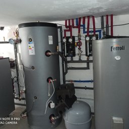 Wojciech woj - Szary, cylindryczny zbiornik Galmet z etykietą energetyczną, obok zbiornik Ferroli, rury w izolacji, manometry i zawory. Instalacja w kotłowni.