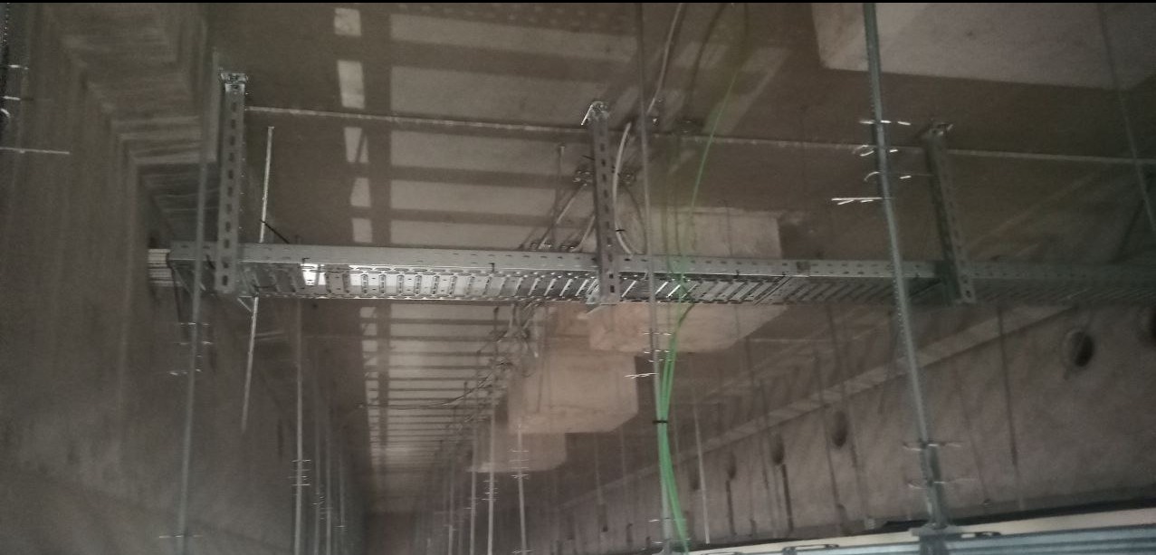 Metalowe korytka kablowe pod sufitem, widoczne przewody. Realizacja w Łodzi. Nietypowe ujęcie instalacji.