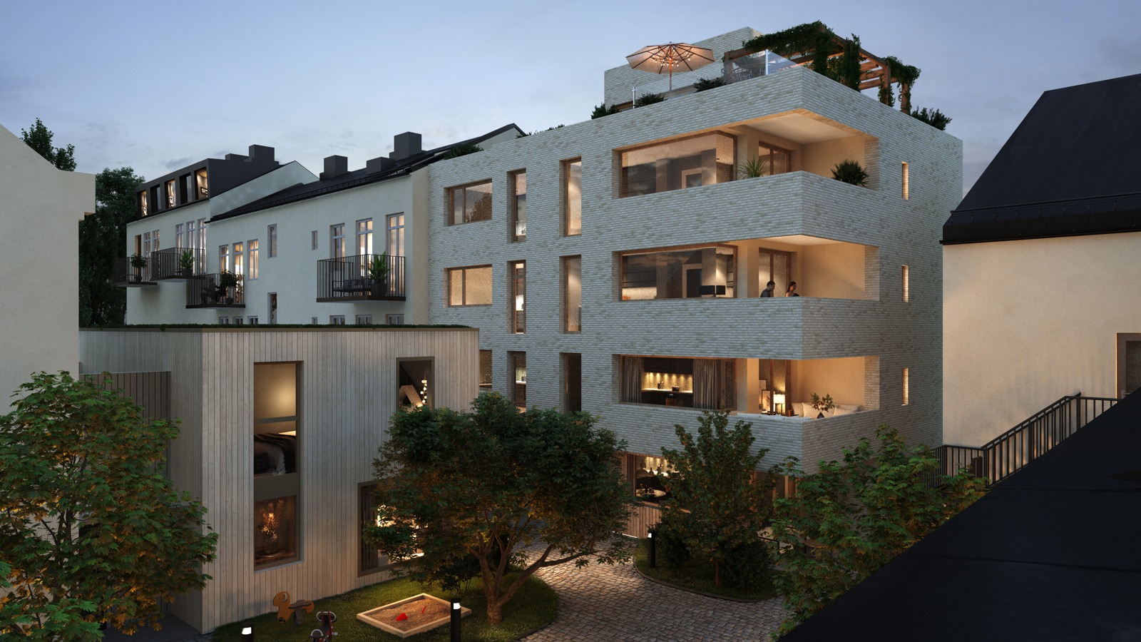 Nowoczesny budynek wielorodzinny z balkonami i tarasem na dachu, oświetlony wieczornym światłem, otoczony zielenią i elementami małej architektury.
