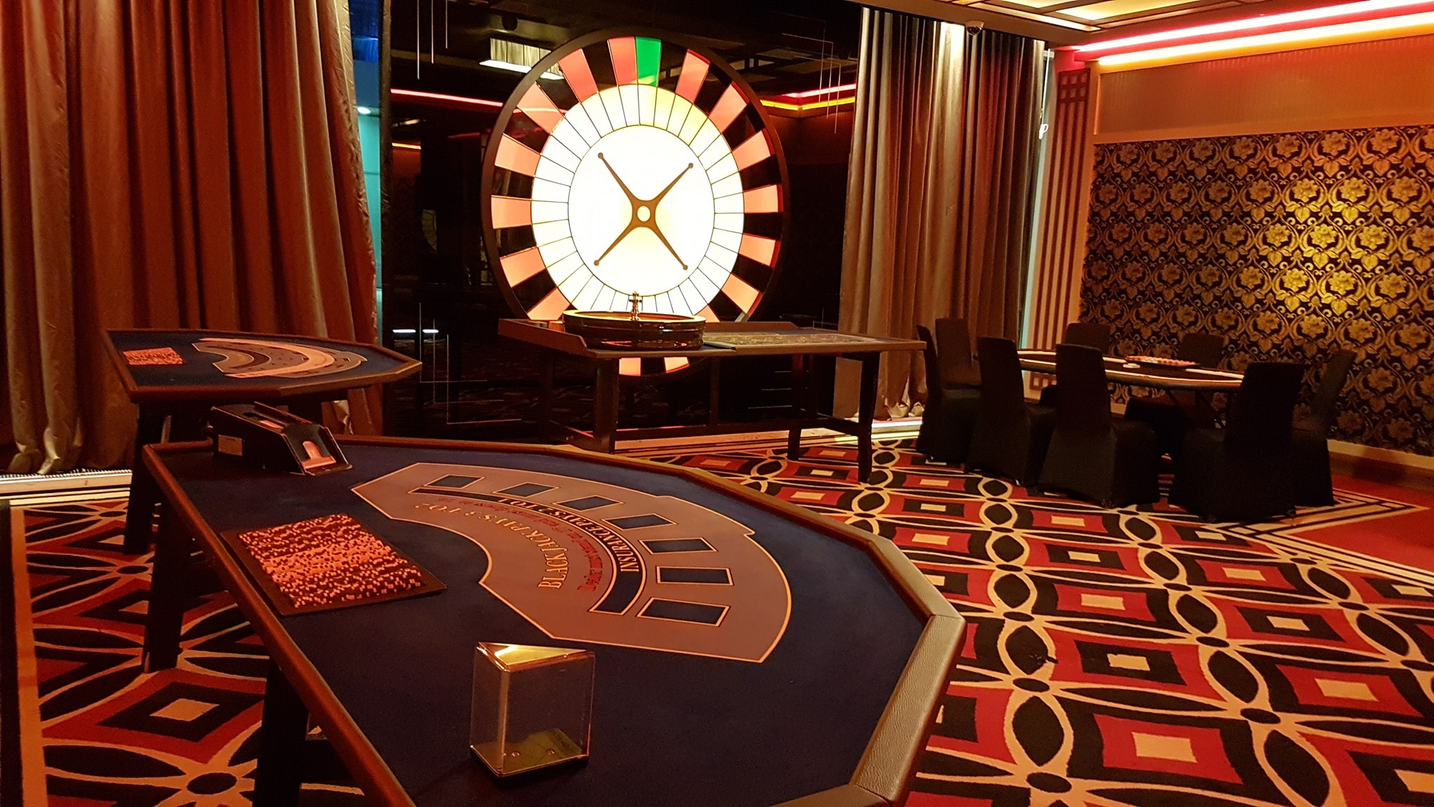 Stylowe kasyno z ruletką, stołami do blackjacka i pokera, eleganckim wystrojem w odcieniach złota i czerwieni, tworzące ekskluzywną atmosferę imprezy tematycznej.