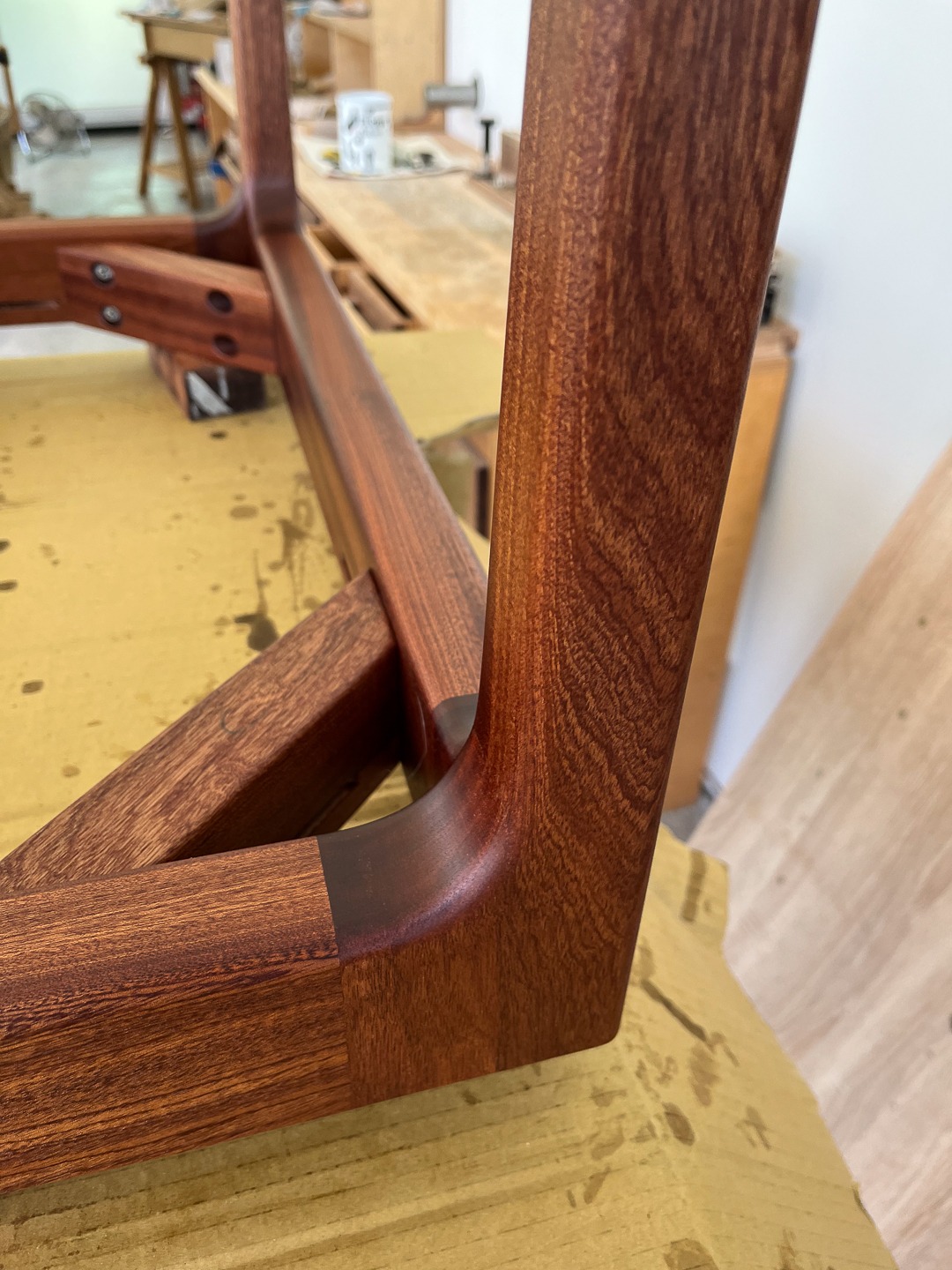 Detal ramy krzesła z egzotycznego drewna o gładkim wykończeniu, ukazujący precyzyjne połączenia i unikalny rysunek słojów. Widoczne ślady obróbki.