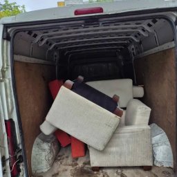 KM KRAS - Wnętrze białego busa wypełnione różnokolorowymi pufami i fotelami z drewnianymi nóżkami. Widoczne ślady na podłodze i elementy karoserii pojazdu.