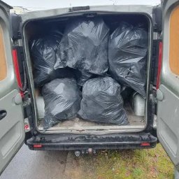 KM KRAS - Wnętrze srebrnego busa wypełnione czarnymi workami na śmieci, widok z tyłu, otwarte drzwi. Transport odpadów po remoncie lub wyburzeniu.