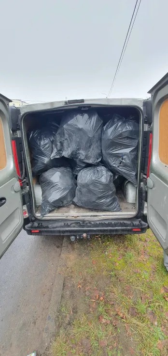 Wnętrze srebrnego busa wypełnione czarnymi workami na śmieci, widok z tyłu, otwarte drzwi. Transport odpadów po remoncie lub wyburzeniu.