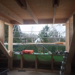 Aqua remont &secobau - Drewniana konstrukcja dachu w trakcie budowy w Zielonej Górze. Widoczne narzędzia, drabina i elementy konstrukcyjne.