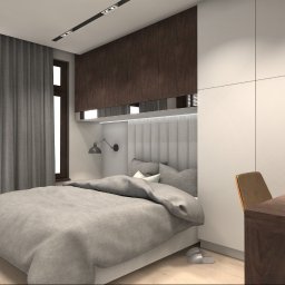Koddo design - Nowoczesna sypialnia z szarą tapicerowaną ścianą za łóżkiem, drewnianymi szafkami i biurkiem. Stonowana kolorystyka, minimalistyczny design, lampka nocna i zasłony.