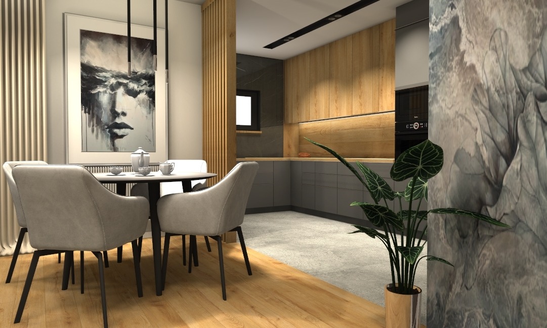 Stylowa jadalnia z okrągłym stołem i szarymi krzesłami. W tle drewniana zabudowa kuchenna i abstrakcyjny obraz na ścianie. Całość dopełnia roślina doniczkowa.
