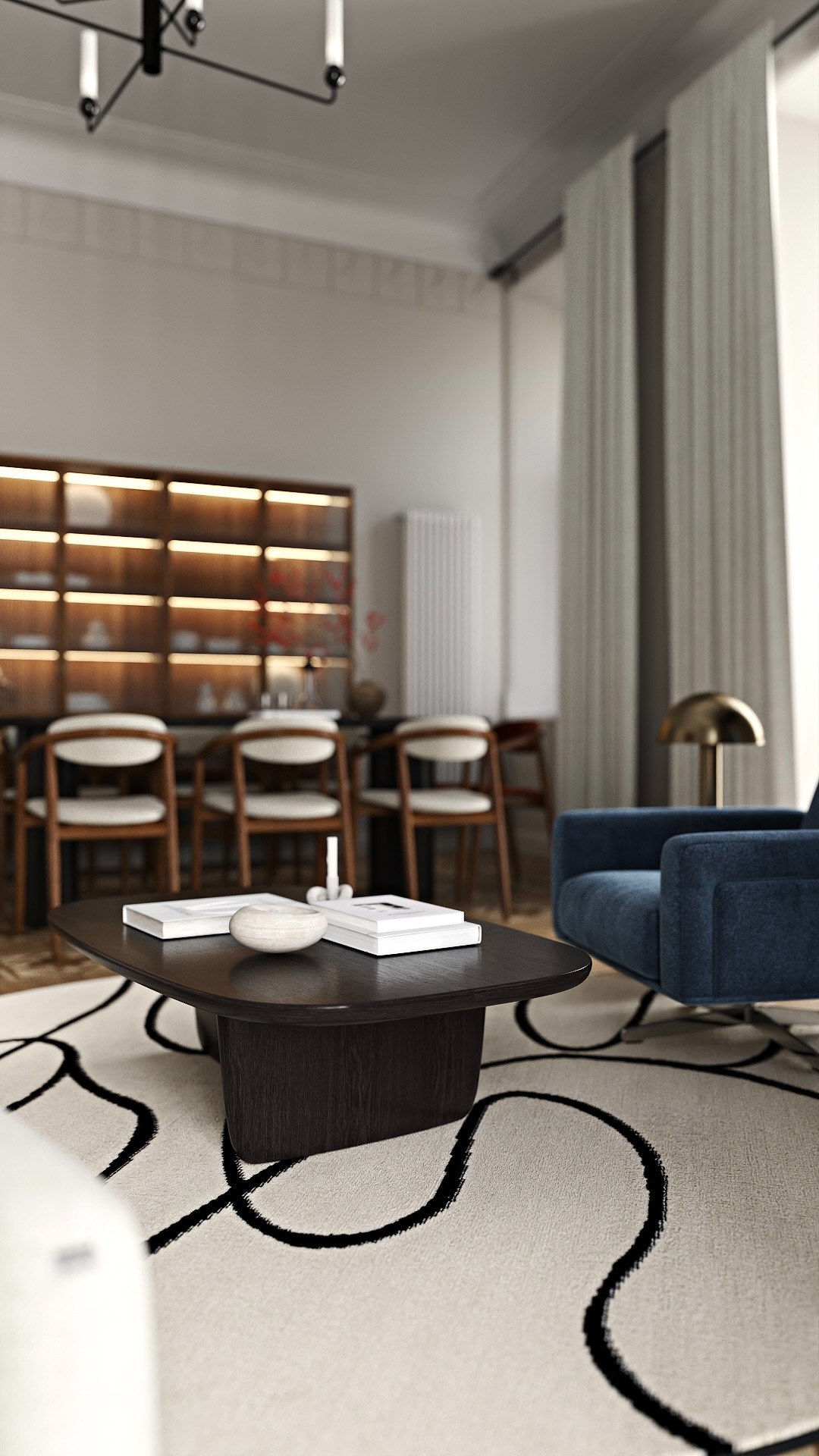 Stylowe wnętrze: ciemny stolik kawowy z książkami i dekoracją na wzorzystym dywanie, w tle krzesła, regał z oświetleniem i niebieski fotel z lampą.