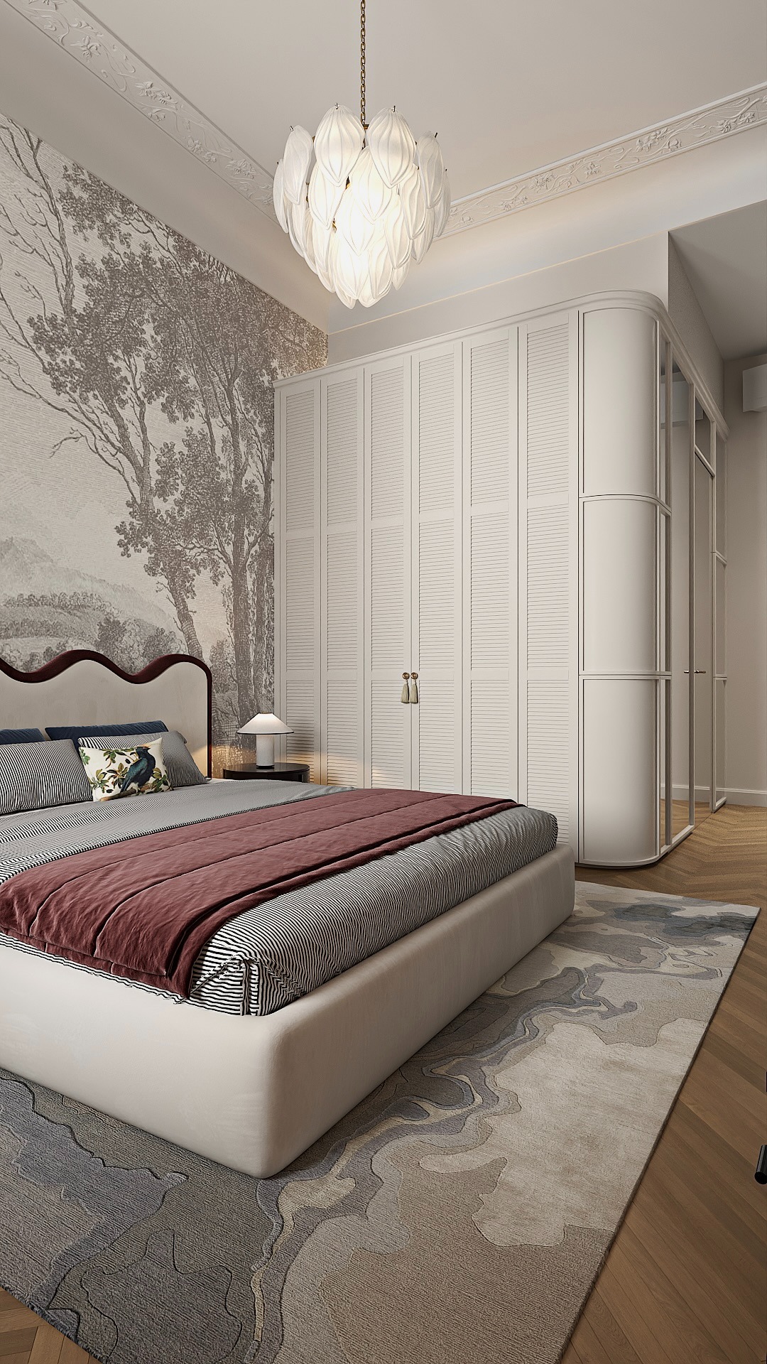 Elegancka sypialnia z tapetą w motywy drzew, dużą szafą z żaluzjowymi drzwiami i designerską lampą. Stonowana kolorystyka, drewniana podłoga i wzorzysty dywan.