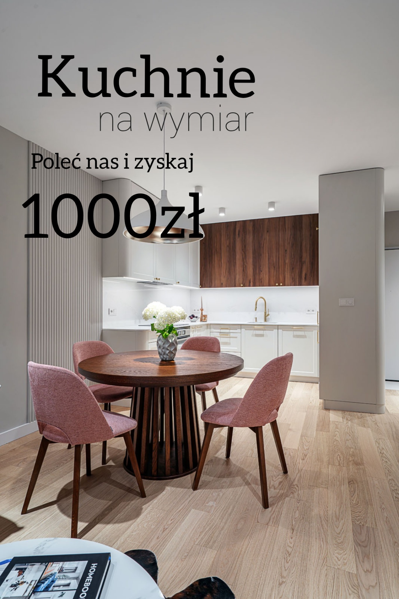 Jasna kuchnia z drewnianymi akcentami i okrągłym stołem z różowymi krzesłami. Nad stołem wisi nowoczesna lampa. Na zdjęciu widoczny napis 'Kuchnie na wymiar'.