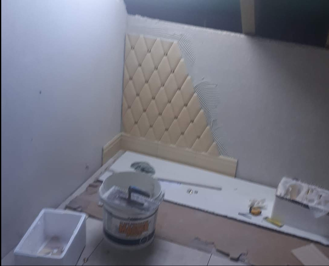 Montaż dekoracyjnych paneli ściennych w romby, widoczny klej i narzędzia glazurnicze. Prace wykończeniowe w pomieszczeniu ze skosem.