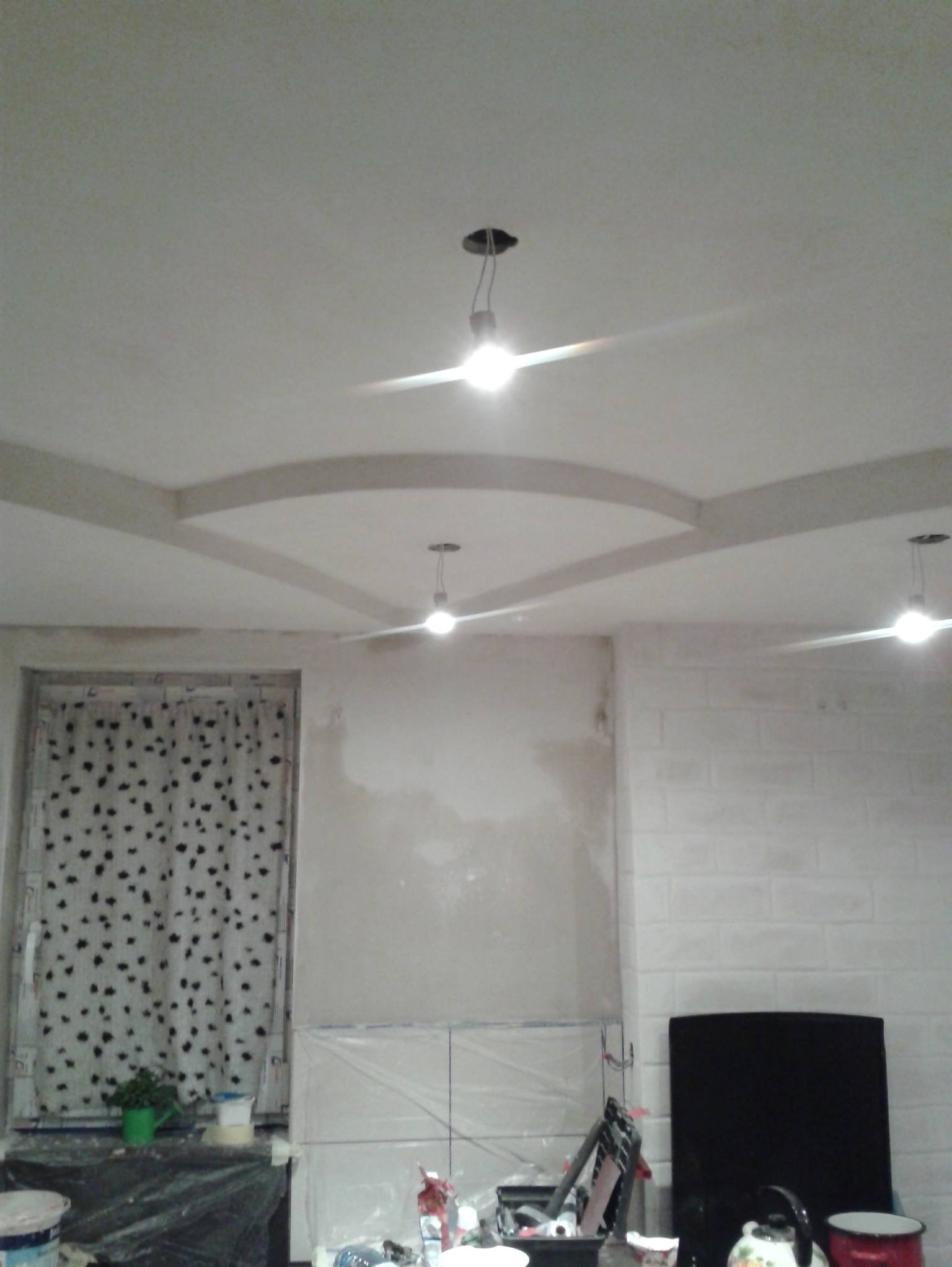 Remont pokoju: sufit z dekoracyjnymi listwami, ściany w trakcie malowania, okno z zasłoną w kropki. Widoczne narzędzia i materiały malarskie.