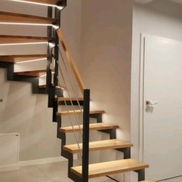 Malar - Nowoczesne schody metalowe z drewnianymi stopniami i podświetleniem LED, minimalistyczny design, jasne wnętrze, widok z dołu, eleganckie wykończenie.