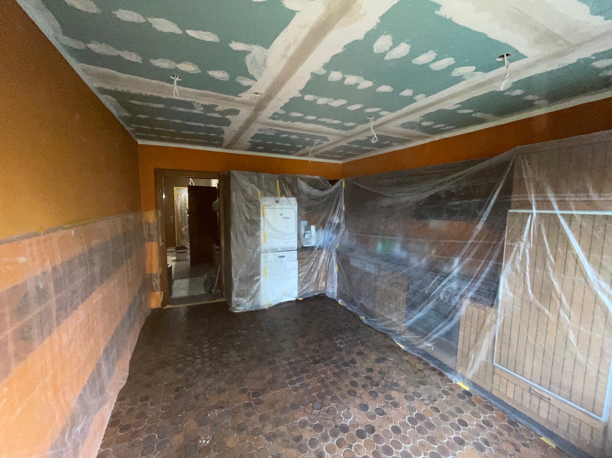 Pokój w trakcie remontu: sufit z płyt karton-gips, ściany zabezpieczone folią, widoczne instalacje elektryczne. Przygotowanie do malowania.