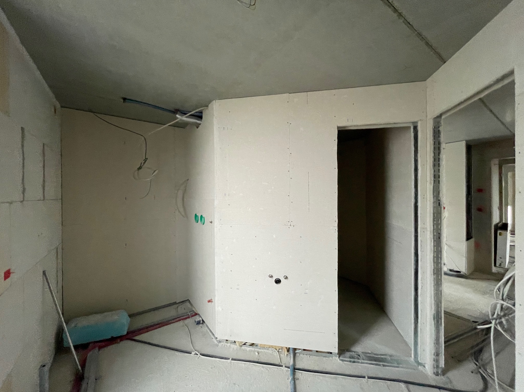 Wnętrze w trakcie remontu: ściany z płyt karton-gips, widoczne instalacje, surowy betonowy sufit. Przygotowanie do dalszych prac wykończeniowych.