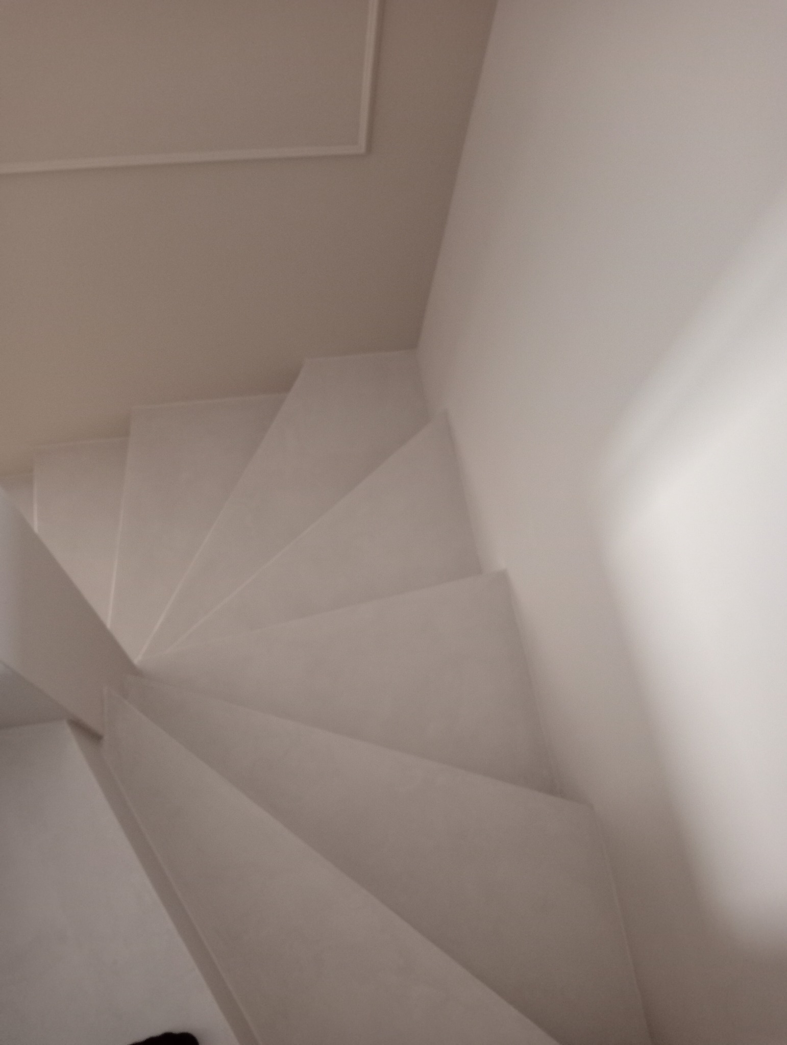 Minimalistyczne, białe schody z gładką powierzchnią, widziane z góry, z subtelnym oświetleniem i prostą listwą sufitową w tle. Nowoczesne wykończenie.