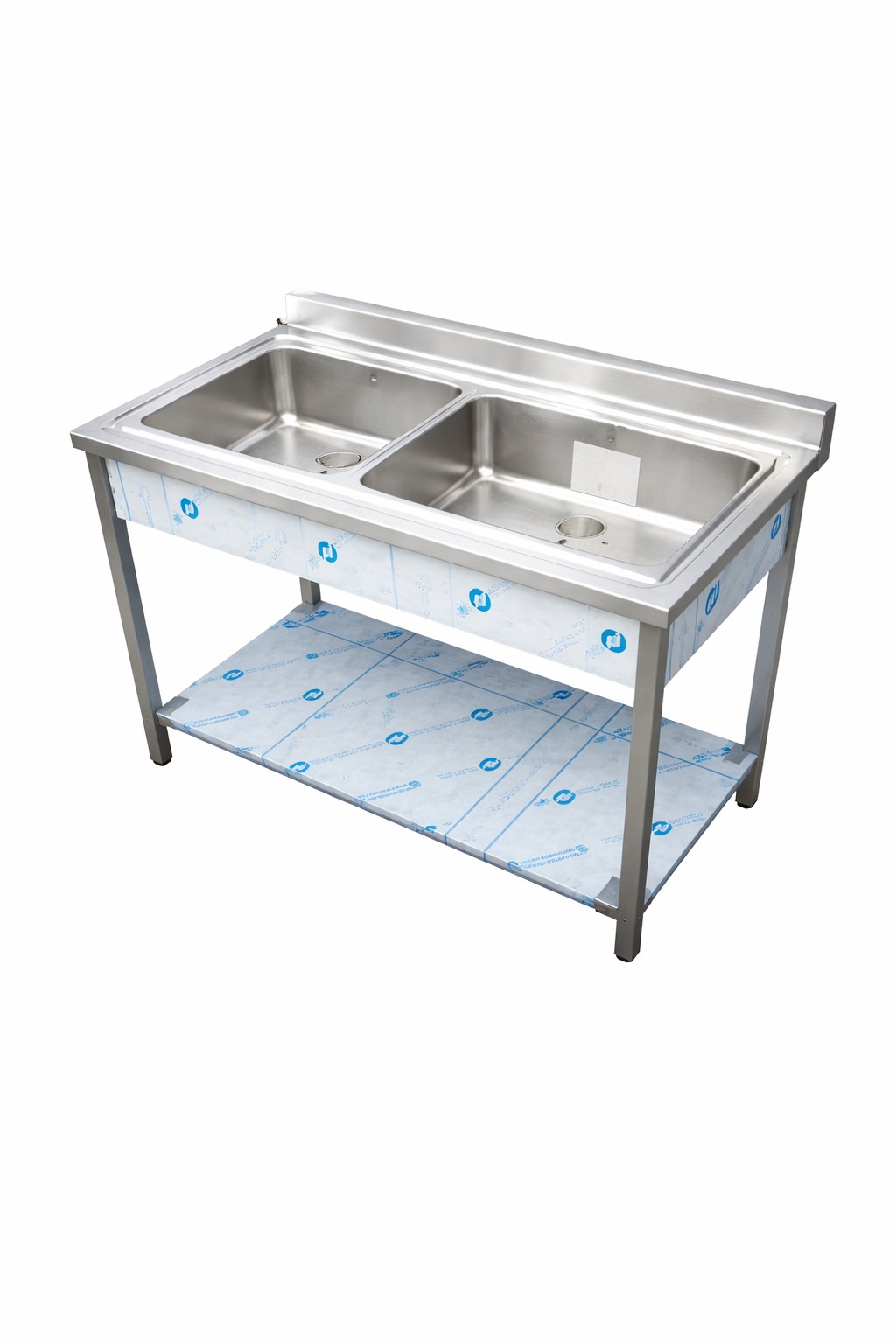 Stalowy stół roboczy z dwoma zlewozmywakami, z dolną półką, zabezpieczony folią ochronną. Widok z przodu na białym tle.