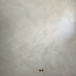 MTM Renowacje - Ściana z efektem dekoracyjnym w odcieniach szarości, zabezpieczona taśmą malarską przy podłodze. Widoczne gniazdka elektryczne.