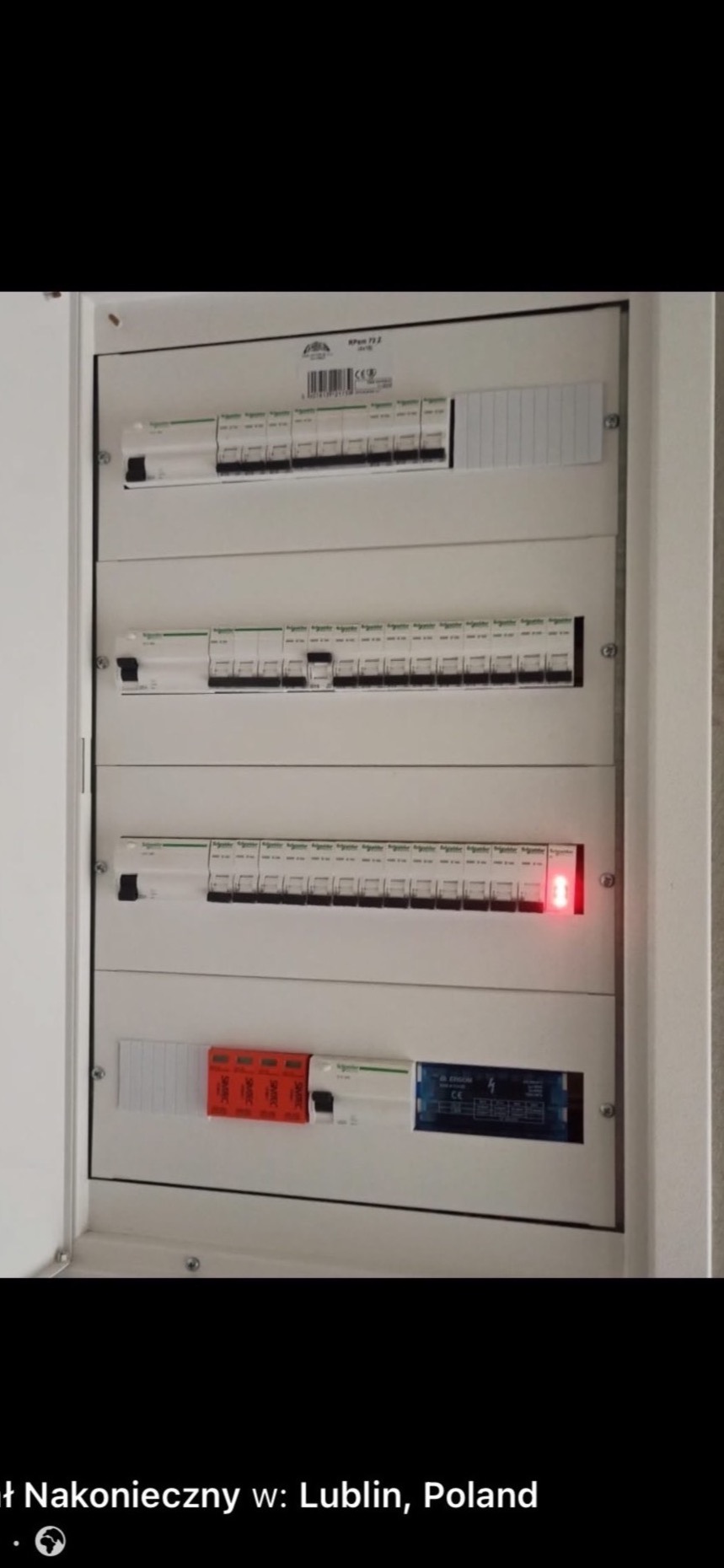 Rozdzielnica elektryczna z bezpiecznikami, jeden z nich sygnalizuje awarię czerwoną diodą. Widoczne oznaczenia producenta i parametry techniczne.