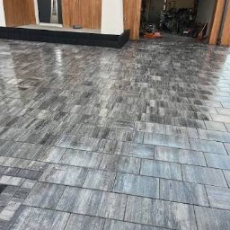 Vasyl Yaskovets - Ułożona, szara kostka brukowa na podjeździe z widocznym wejściem do garażu i domu. Kostka ułożona w regularny wzór, z widocznymi fugami.