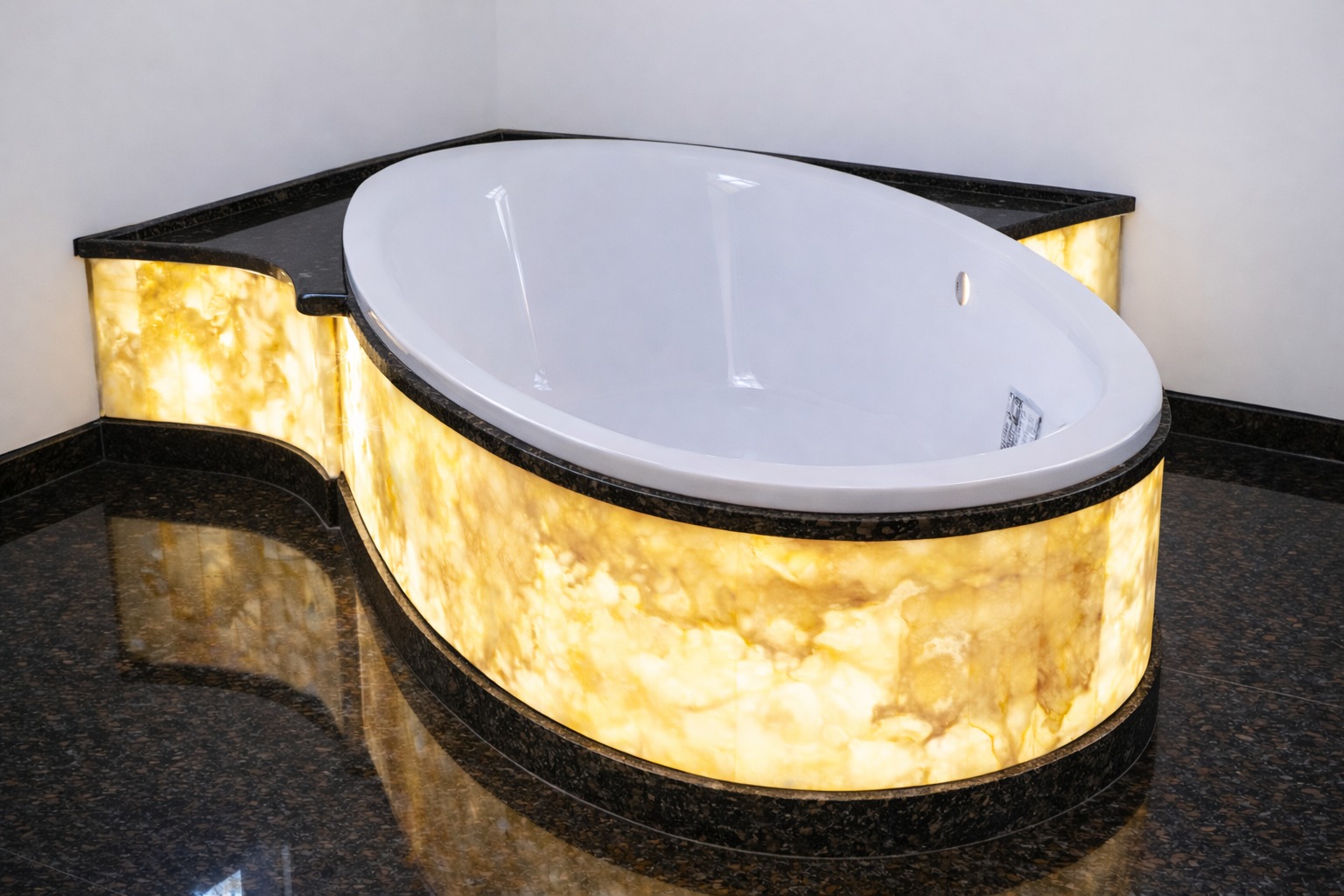 Owalna wanna z podświetlaną obudową z onyksu, obramowana ciemnym kamieniem. Podłoga wyłożona ciemnymi płytkami. Nowoczesny design łazienki.