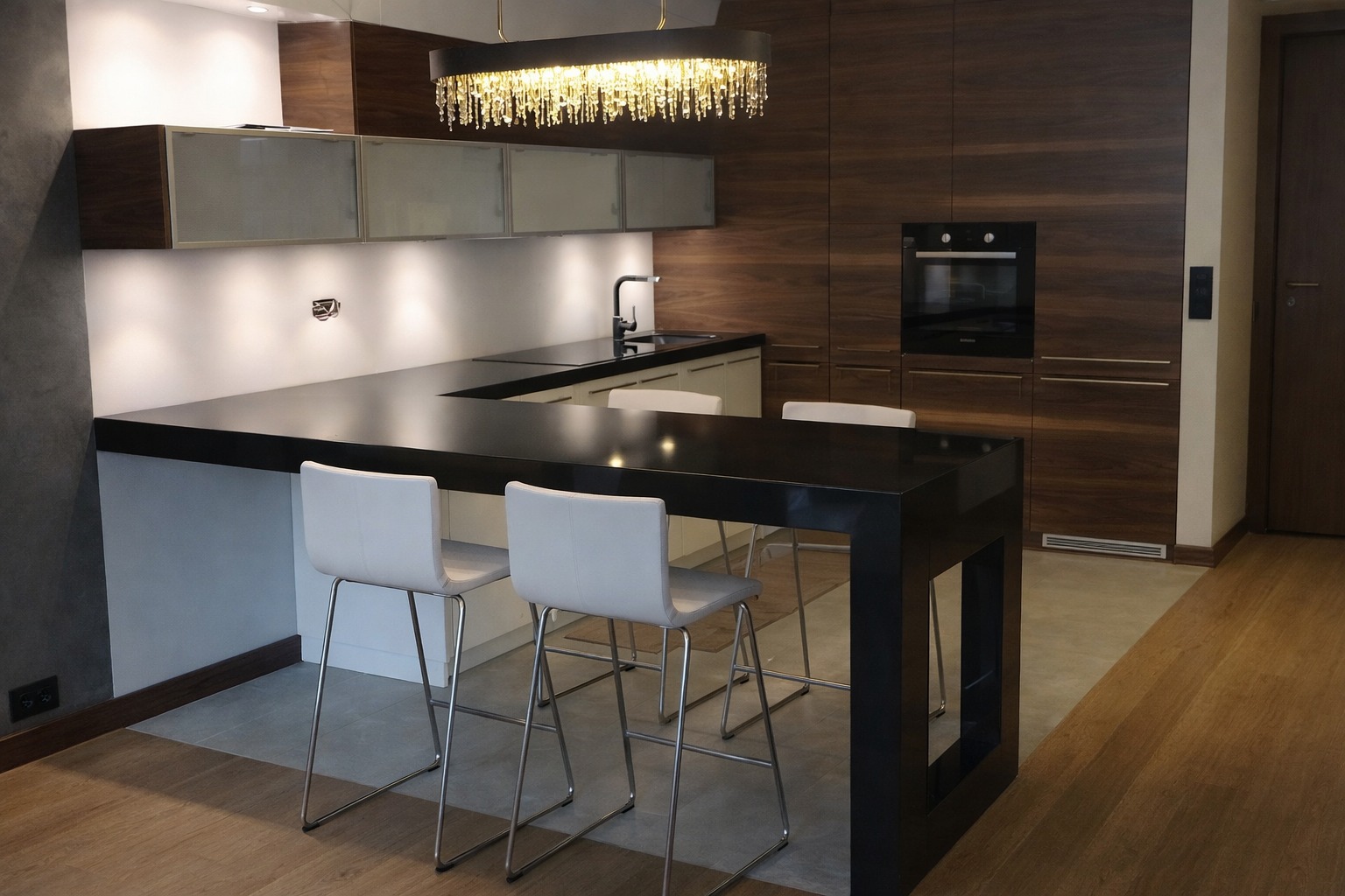 Nowoczesna kuchnia w Wiązownie z czarnym blatem kamiennym i barkiem. Minimalistyczne krzesła barowe, oświetlenie LED i drewniane szafki tworzą elegancką przestrzeń.