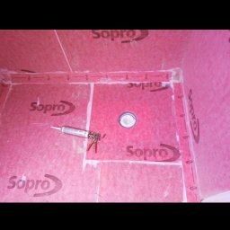 AM AUREUS WYKOŃCZENIA WNĘTRZ - Hydroizolacja pod płytki w łazience. Widoczna mata uszczelniająca Sopro, odpływ liniowy i aplikator do silikonu. Prace przygotowawcze przed położeniem płytek.