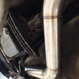 Evo Tune Oborniki Śląskie - Spawany, nierdzewny układ wydechowy pod podwoziem auta, widoczne spawy z charakterystycznymi przebarwieniami termicznymi. Elementy zawieszenia i skrzyni biegów w tle.