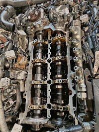 Otwarty silnik samochodowy z widocznymi wałkami rozrządu i elementami układu smarowania, w trakcie naprawy lub przeglądu, z bliska, z góry.