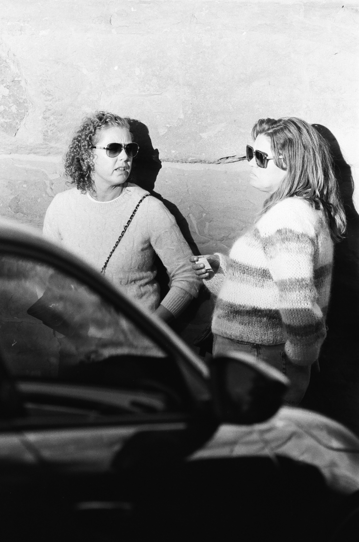 Reportaż - ciekawie oświetlone rozmawiające kobiety i uchwycony przejeżdżający samochód