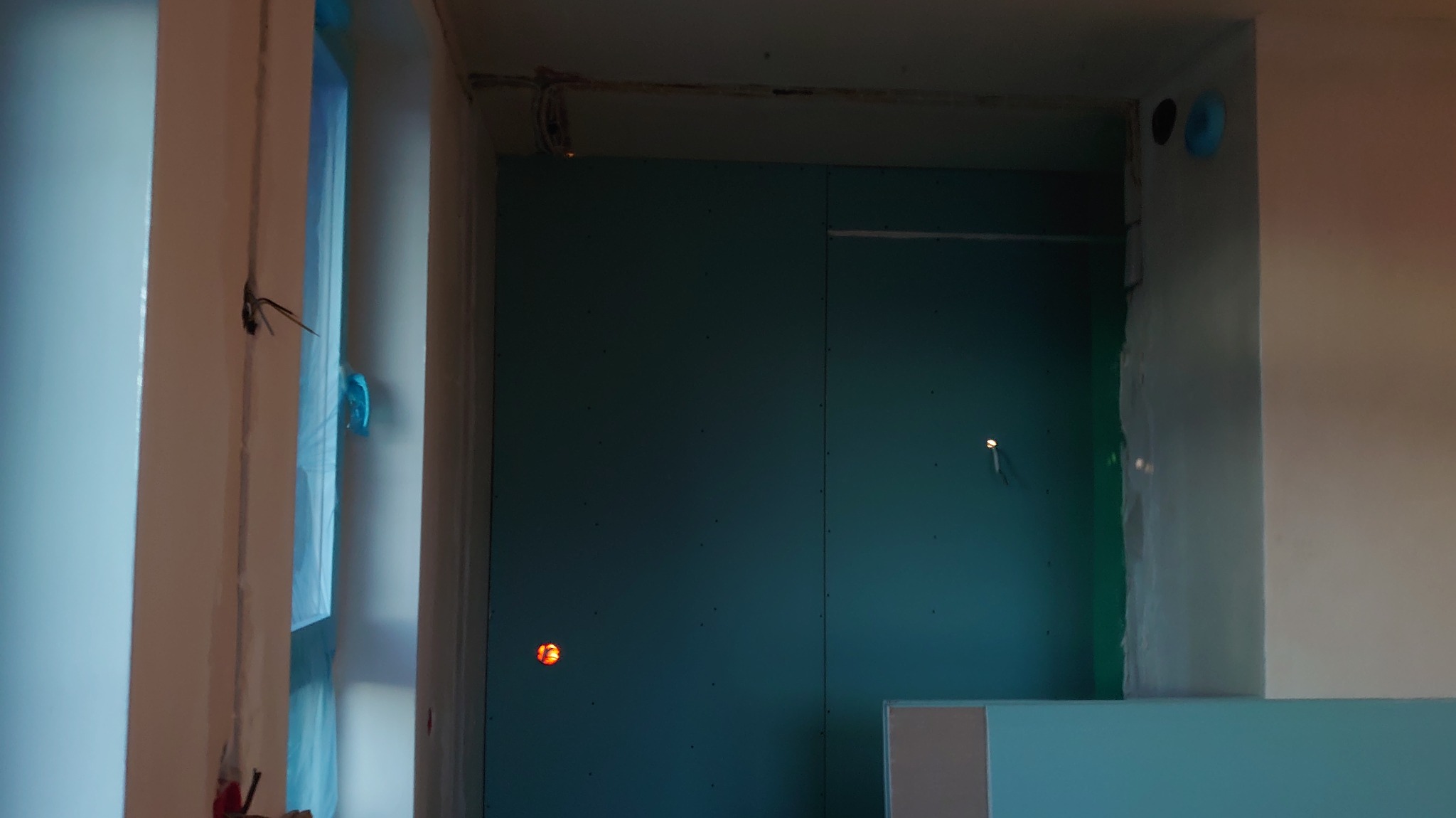 Wnętrze w trakcie remontu: ściany z płyt gipsowo-kartonowych, widoczne przewody elektryczne wystające ze ściany, przygotowane otwory pod gniazdka.