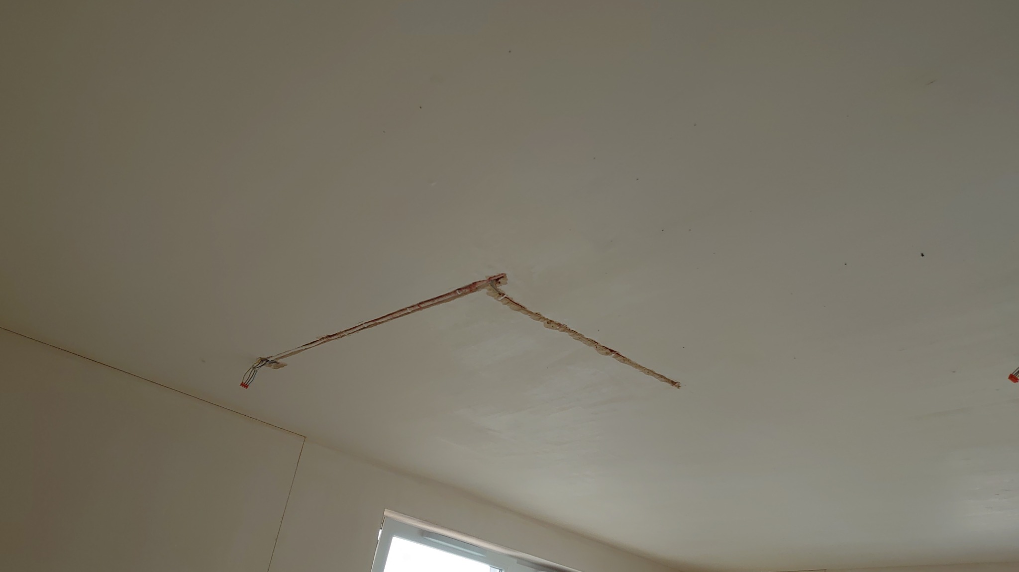 Bruzdy w suficie przygotowane pod kable elektryczne, widoczne przewody. Przygotowanie do montażu oświetlenia w nowym domu. Widok z dołu na sufit.