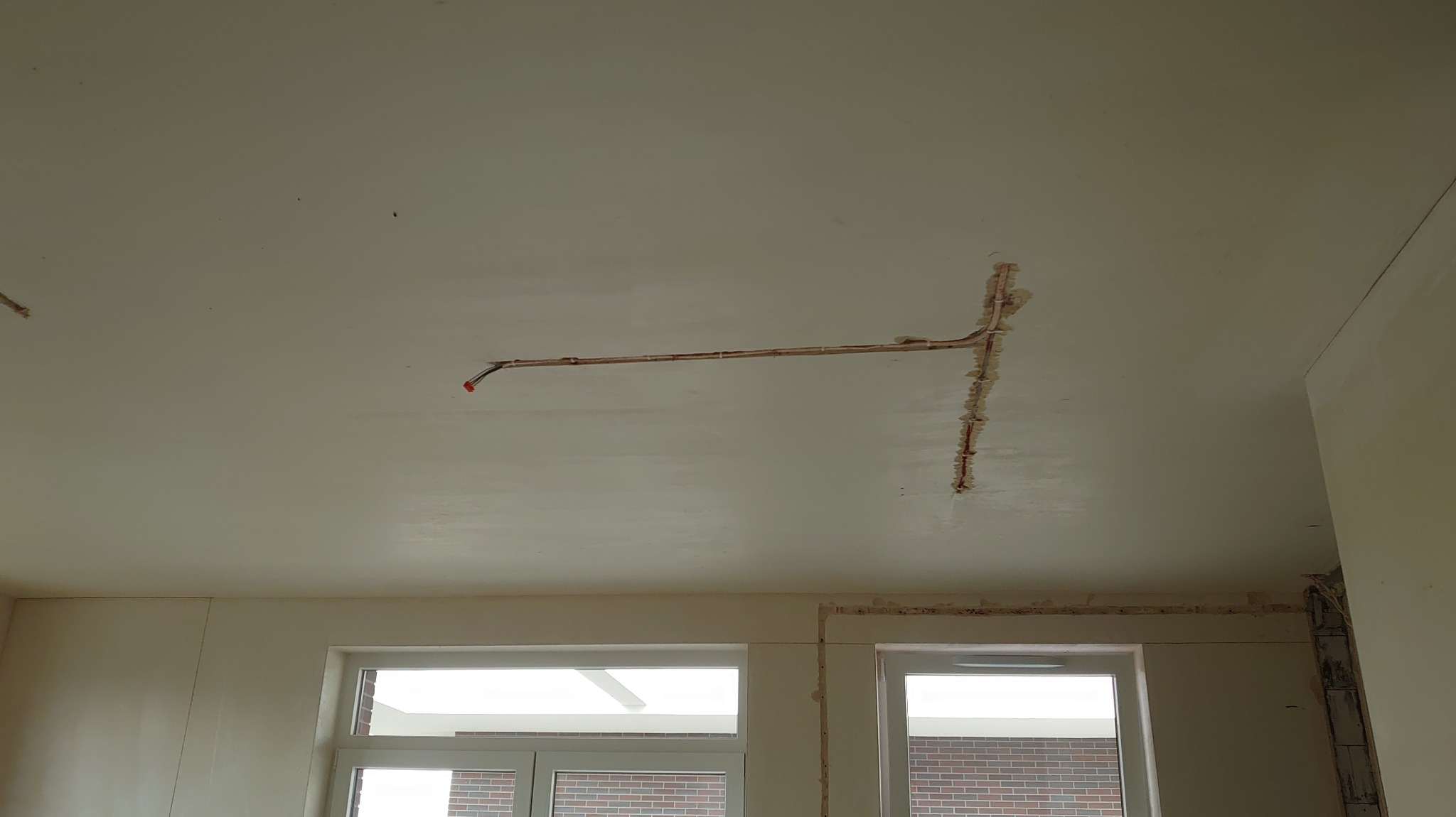 Instalacja elektryczna w bruzdach na suficie w Starym Skoszewie. Widoczne kable i przygotowane otwory pod oświetlenie. Etap prac przed wykończeniem.