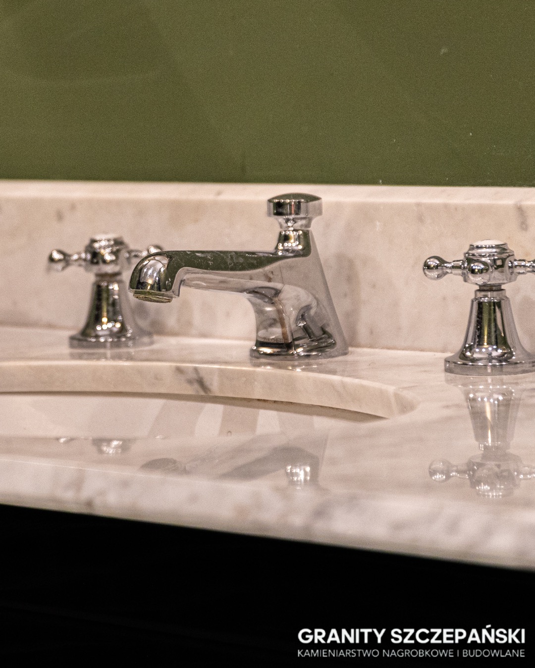 Elegancka umywalka z blatem z jasnego kamienia z wyraźnym użyleniem, chromowana bateria w stylu retro, zielone tło. Detal wykończenia łazienki.