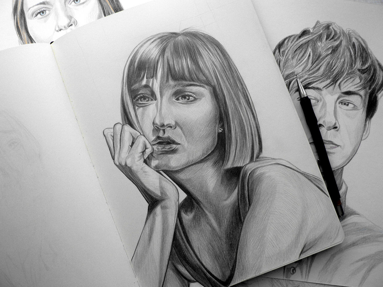 Ołówkowy portret kobiety z bobem, oparty o dłoń, w szkicowniku. W tle inne szkice i ołówek automatyczny. Delikatne cieniowanie, realistyczne proporcje.