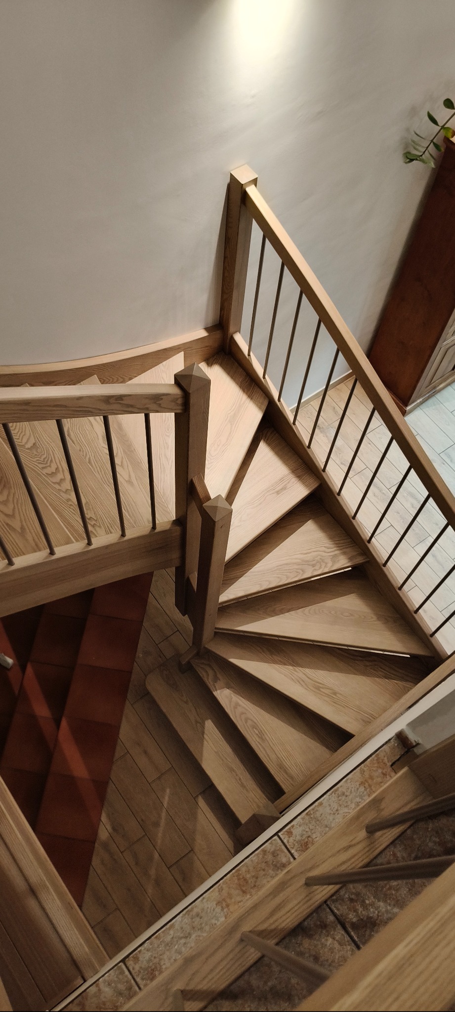 Spiralne schody drewniane z metalową balustradą, widok z góry. Jasne drewno, nowoczesny design, oświetlenie podkreśla strukturę drewna. Element wystroju wnętrza.