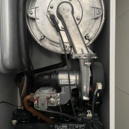 Marcin Hubert - Wnętrze otwartego pieca gazowego Viessmann z widocznymi elementami instalacji, przewodami i elektroniką. Detaliczny widok na komponenty wewnątrz obudowy.