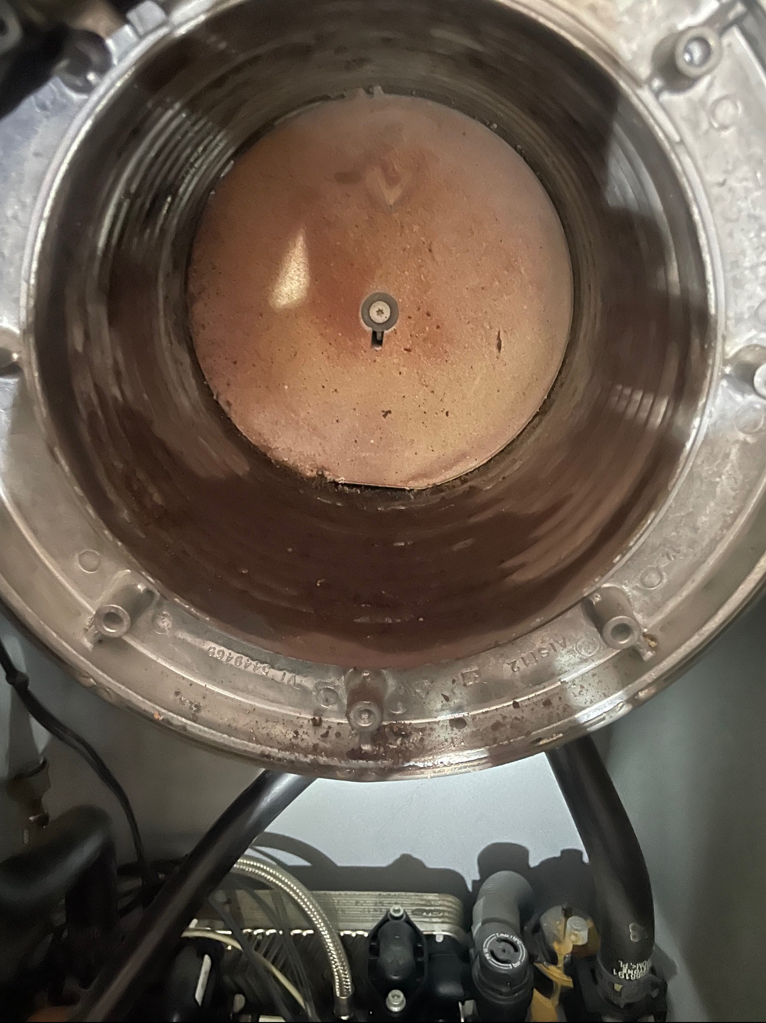 Wnętrze komory spalania pieca gazowego z widocznym palnikiem i elementami instalacji. Widoczne ślady użytkowania i potencjalne zabrudzenia.