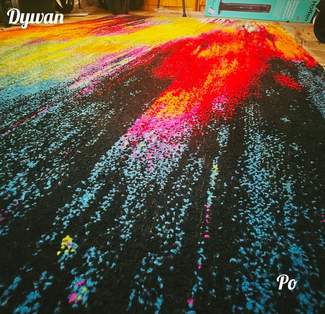 Wyczyszczony, czarny dywan z kolorowymi akcentami (czerwony, żółty, niebieski, różowy) po praniu. Widoczne włókna dywanu i intensywne kolory. Ujęcie z niskiej perspektywy.