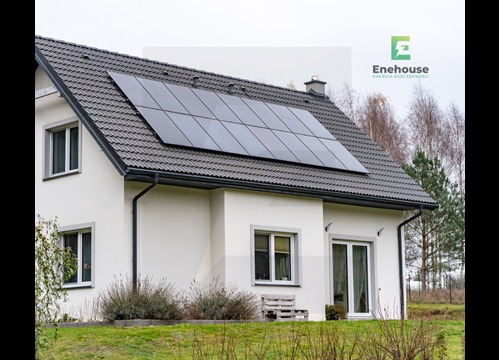 Dom jednorodzinny z panelami słonecznymi na dachu, widok z zewnątrz. Nowoczesna instalacja fotowoltaiczna na tle pochmurnego nieba.