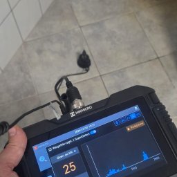 Jacek Babicz - Diagnostyka rur: urządzenie HIKMICRO z ekranem wskazującym parametry dźwiękowe w pomieszczeniu z płytkami. Analiza akustyczna instalacji wodnej.