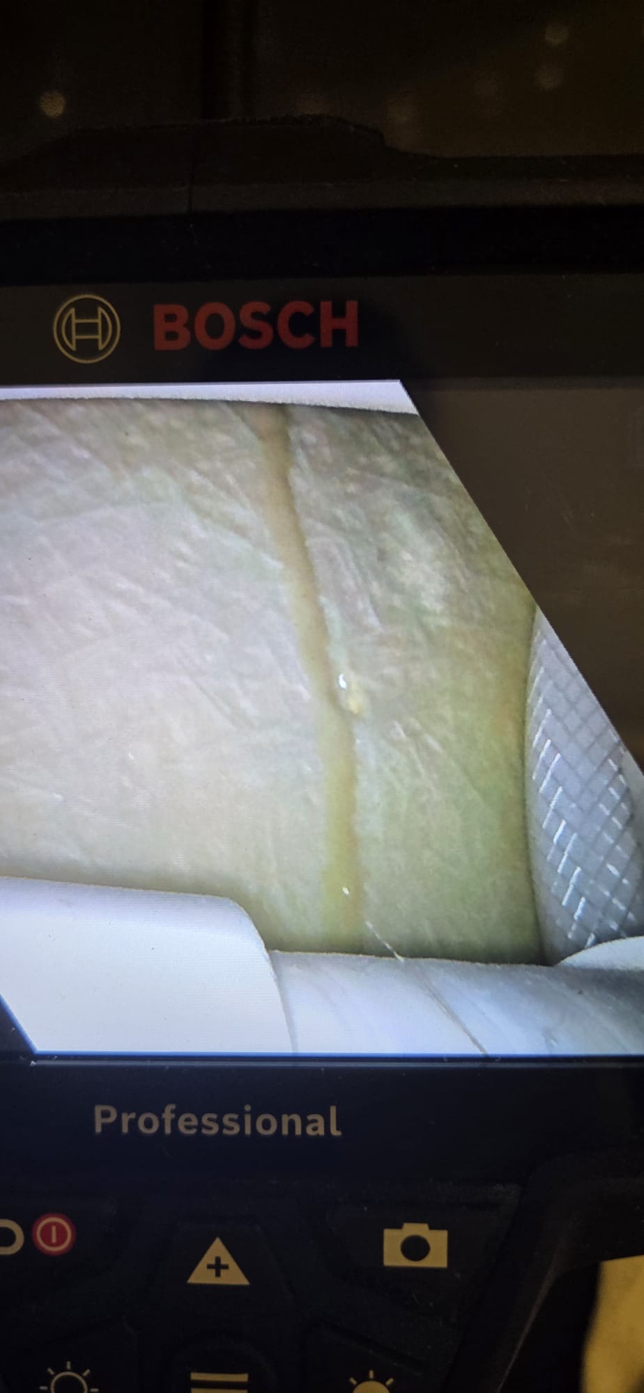 Ekran urządzenia diagnostycznego Bosch pokazuje wnętrze rury z widocznym wyciekiem. Widoczna woda i fragment uszczelnienia. Ujęcie z bliska, oświetlenie LED.