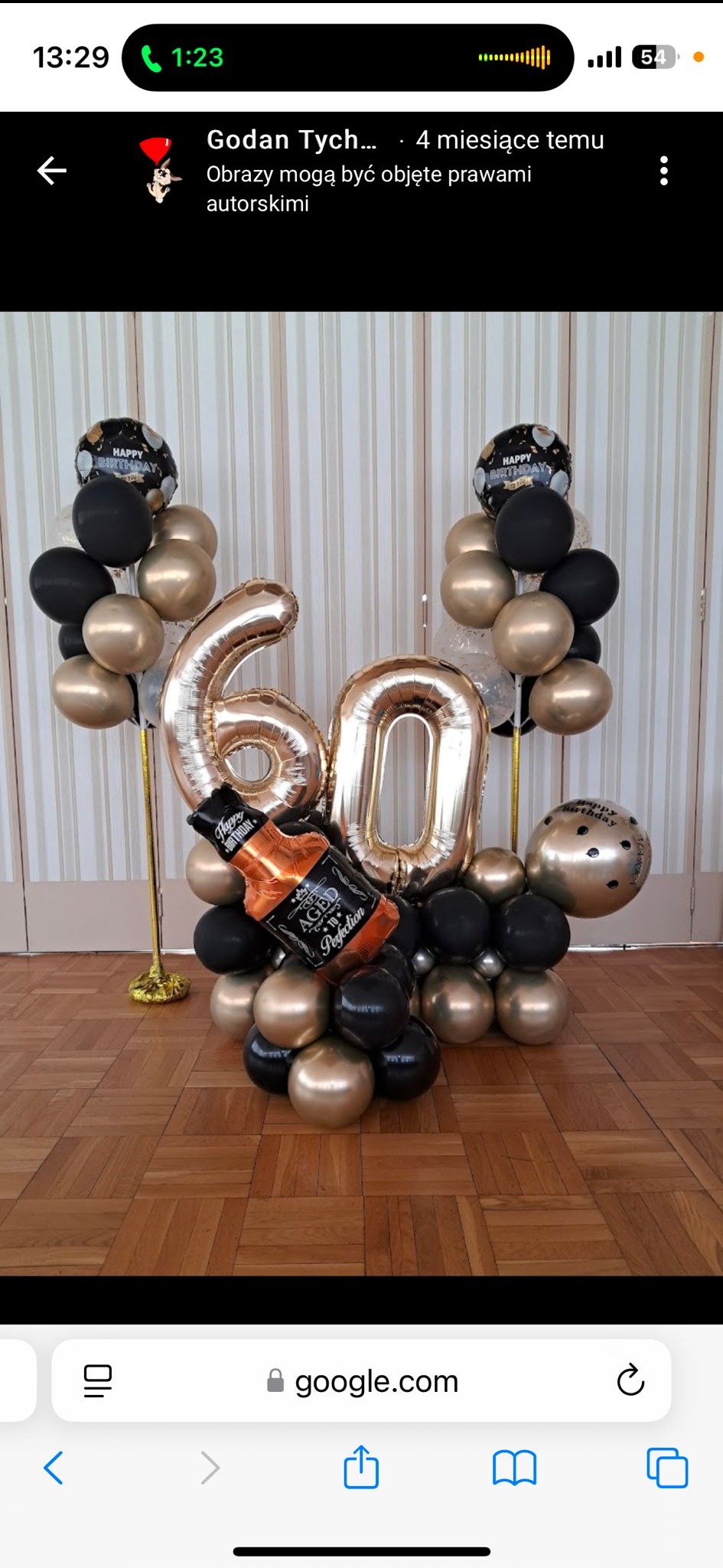 Dekoracja balonowa na 60. urodziny: złote i czarne balony, cyfry '60' z folii, balon w kształcie butelki whisky. Ustawione na drewnianej podłodze.