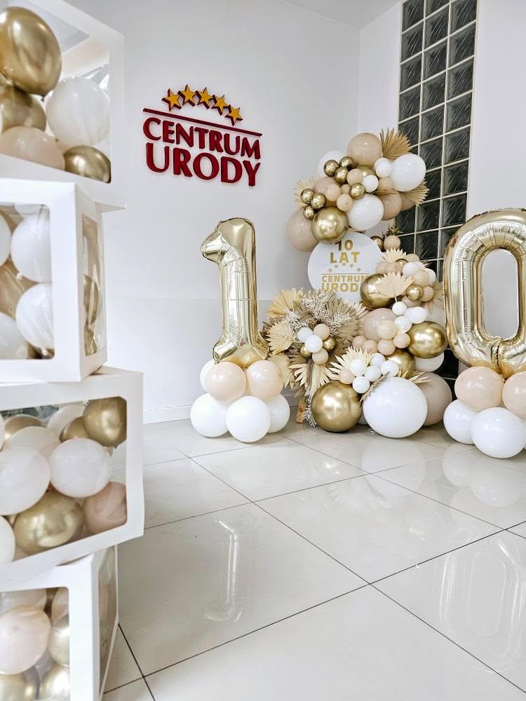 Dekoracja balonowa w odcieniach bieli i złota z okazji 10-lecia Centrum Urody. Balony w pudełkach, cyfry foliowe i kompozycje z suszonych kwiatów.