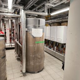 KaBi Hydraulika KAROL BILSKI - Kotłownia z nowymi piecami gazowymi i zbiornikami, rury w izolacji termicznej. Widok na urządzenia przed uruchomieniem, w folii ochronnej.