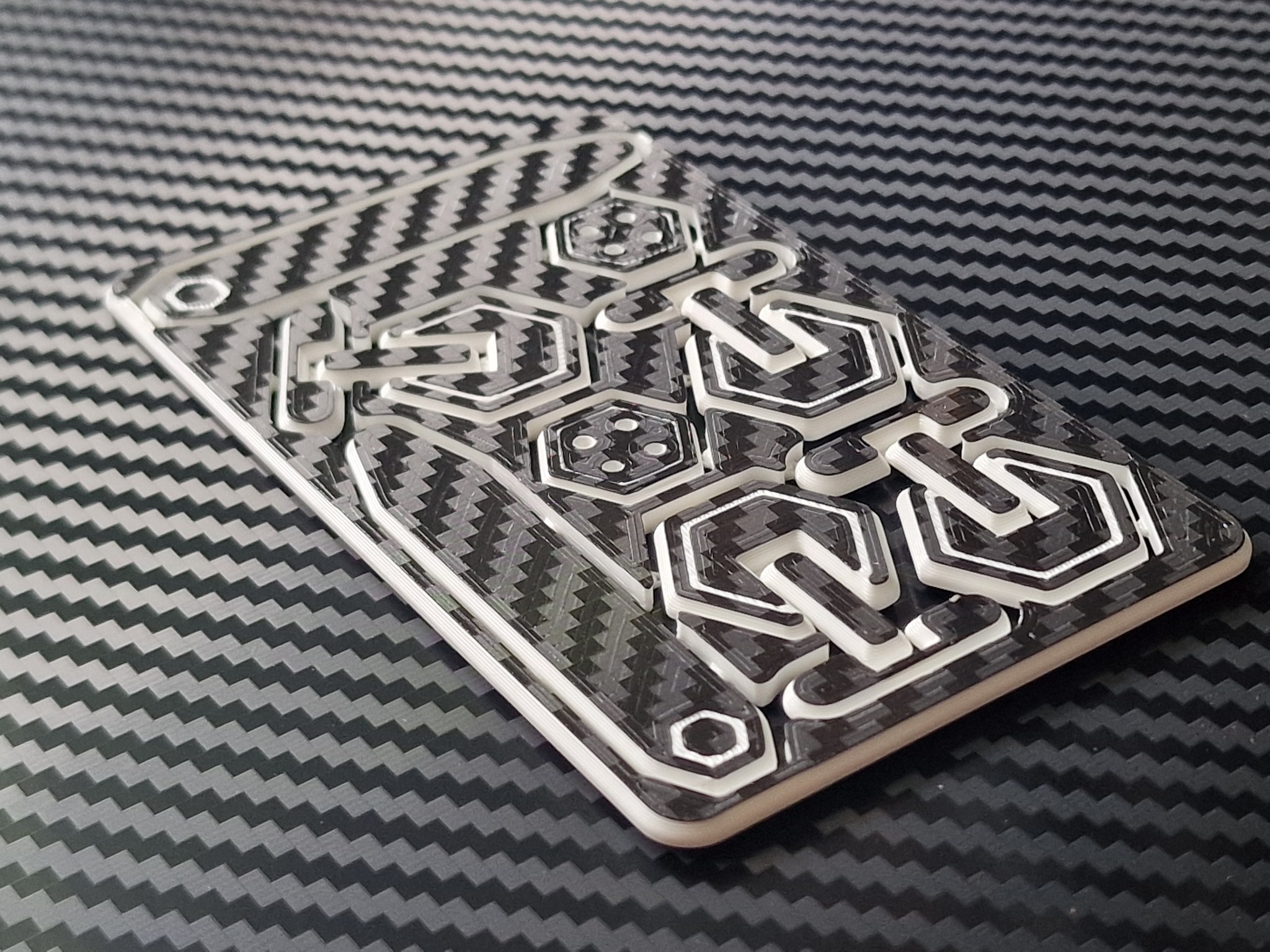 Precyzyjnie wykonany, przezroczysty szablon z wypukłymi wzorami geometrycznymi na tle imitującym włókno węglowe, wykonany w Jankowicach.