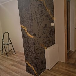 Łukasz Hanas - Dekoracyjna kolumna w pokoju z efektem marmuru i złotymi żyłkami, drabina malarska w tle. Wykończenie wnętrza z dbałością o detale.